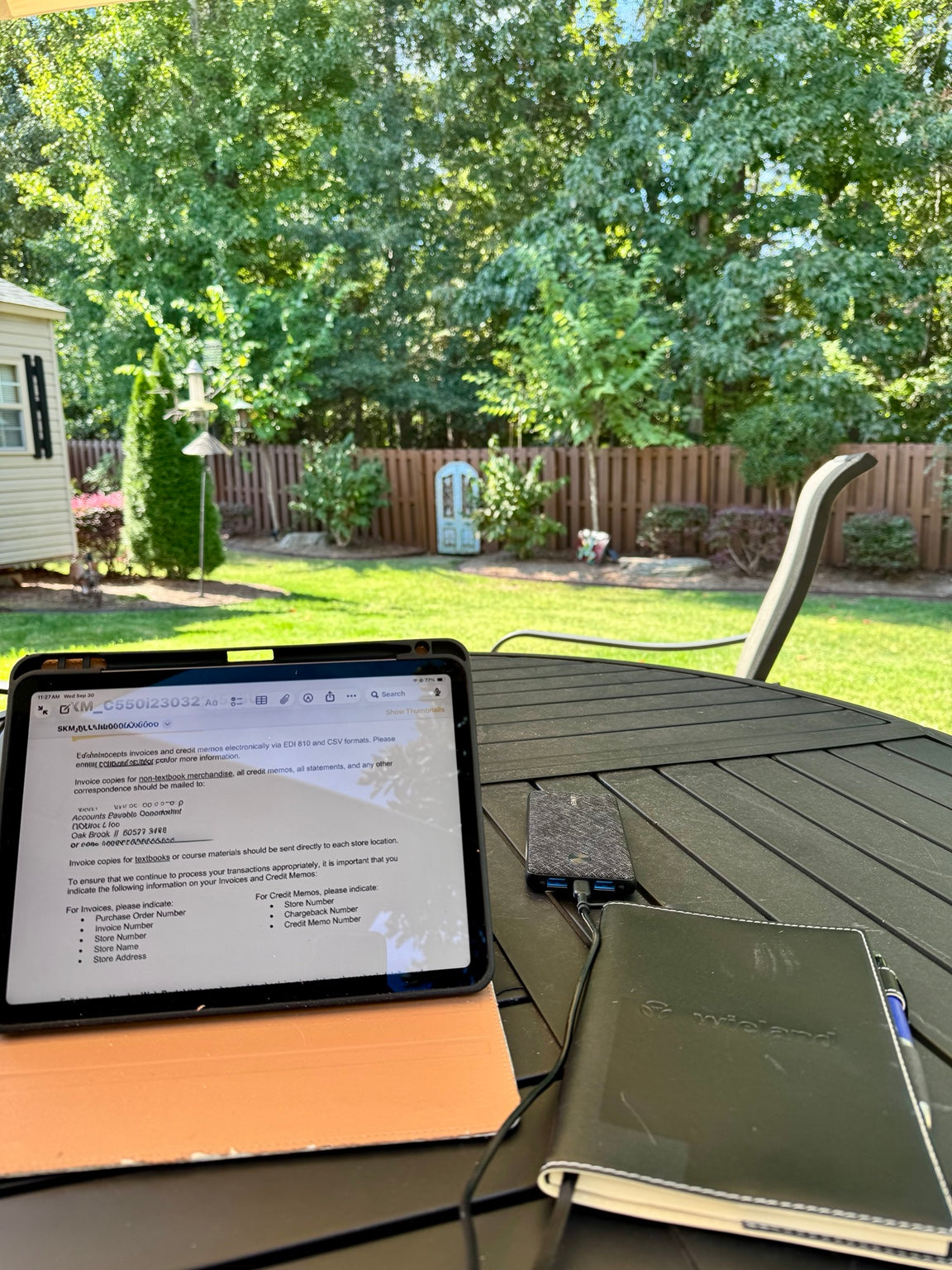An iPad and notebook on Nancy’s patio table, with a sunny backyard beyond.