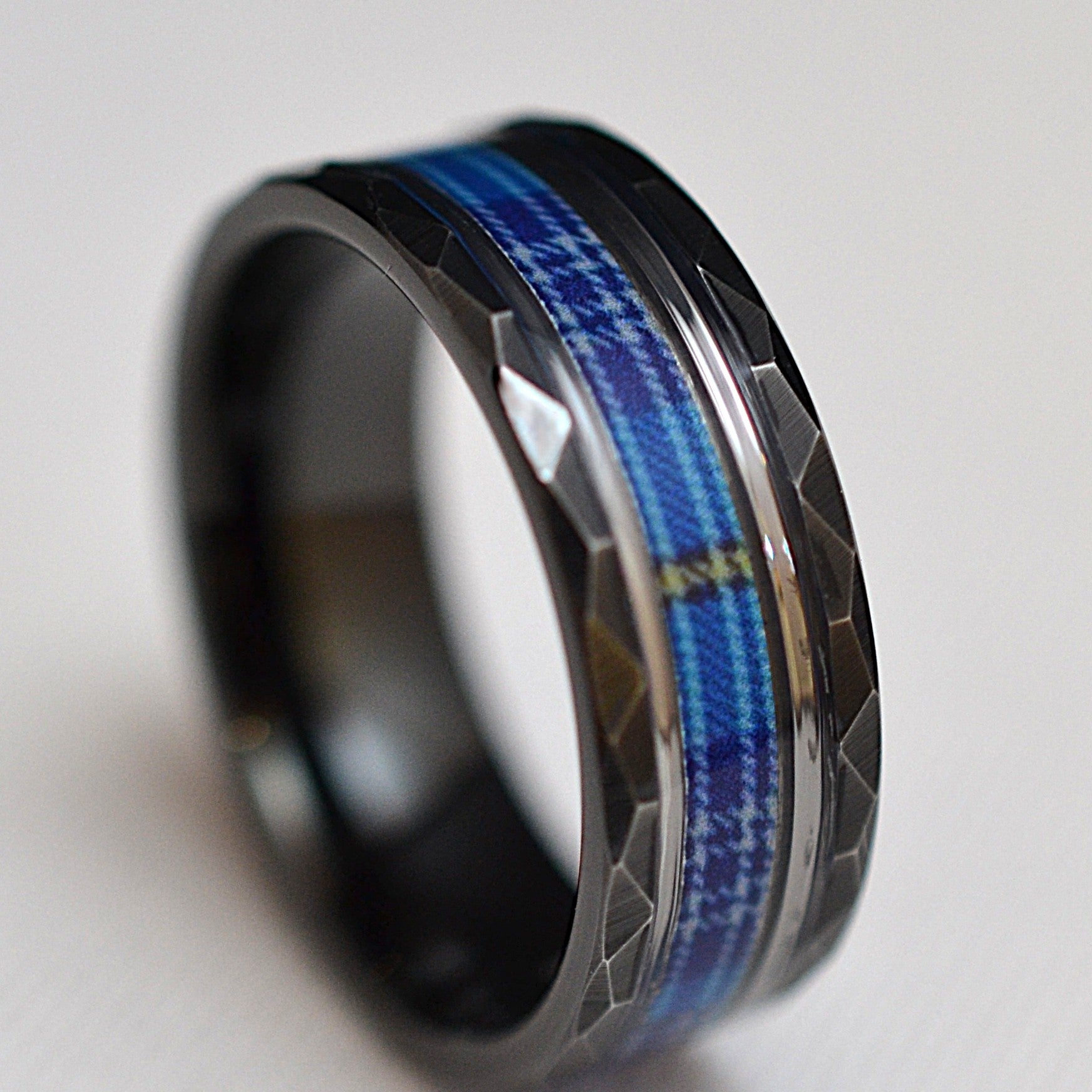 Angled view of handcrafted black tungsten ring featuring The Citadel tartan inlay and polished white gold-plated bands