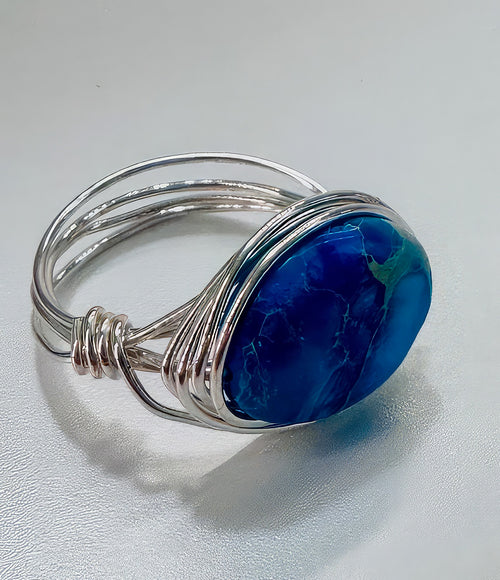 Vibrant blue stunning Aquaterra Jasper stone that looks like a world globe, wrapped in silver wire