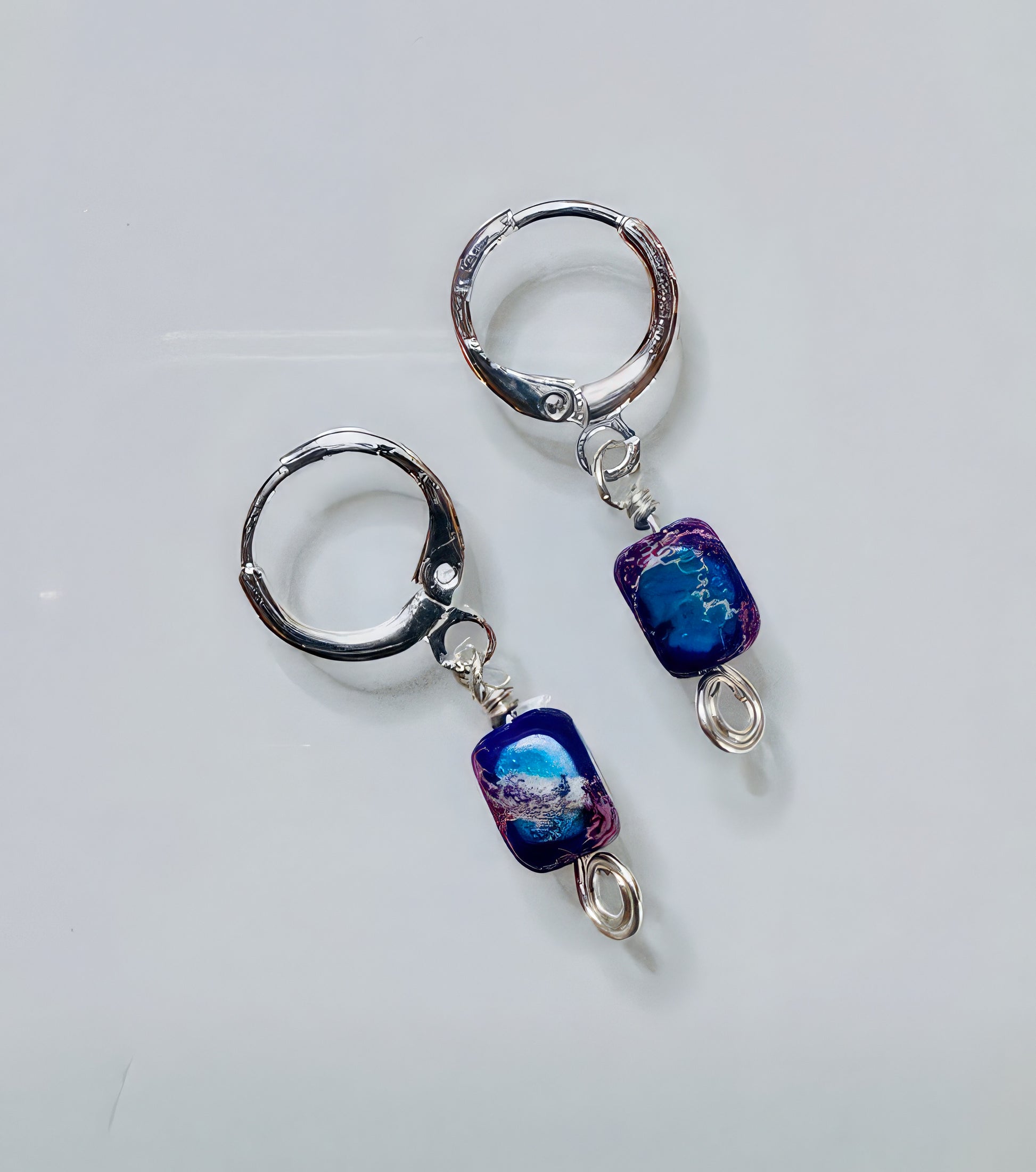 A pair of earrings featuring rounded-corner multicolor stones with hypoallergenic, nickel-free leverback ear wires on a white background.