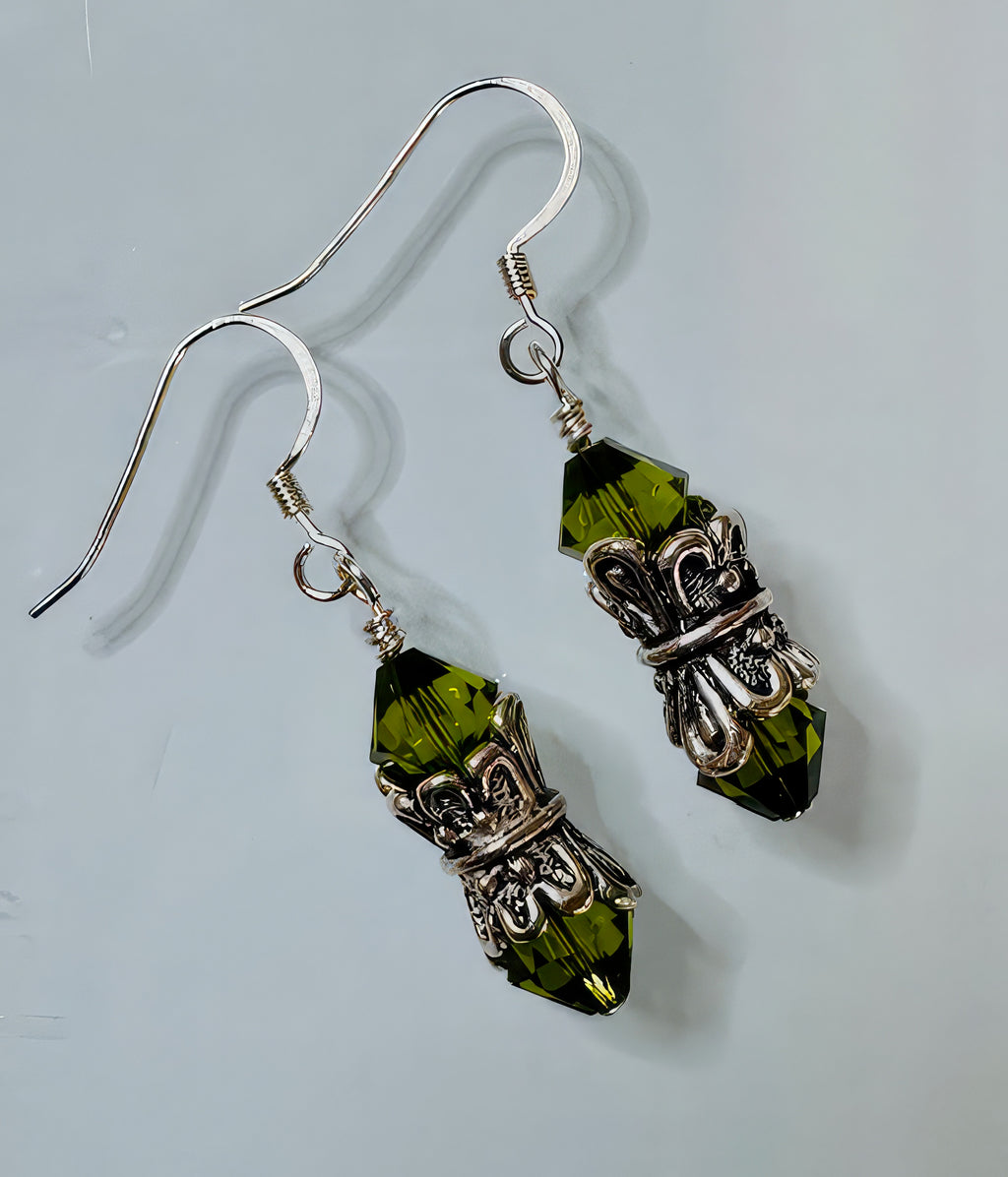 A pair of earrings featuring forest green Swarovski crystals set in antiqued silver collars with sterling silver earwires.