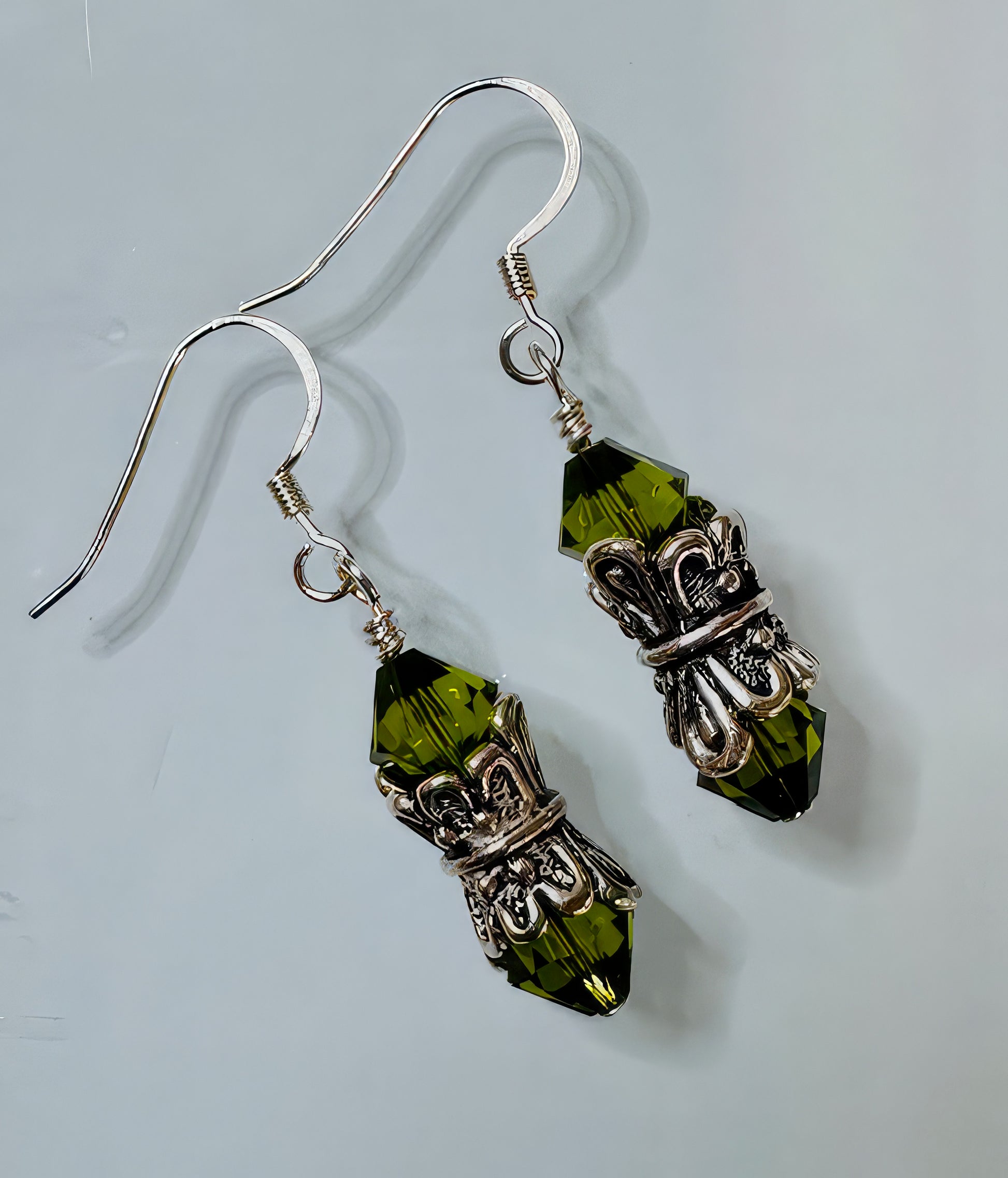 A pair of earrings featuring forest green Swarovski crystals set in antiqued silver collars with sterling silver earwires.