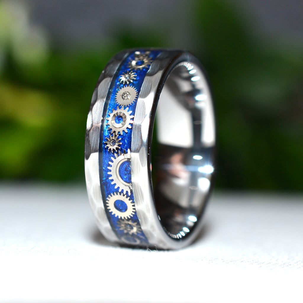 Angled view of the Timekeeper faceted tungsten ring showcasing miniature vintage watch gears individually arranged in a handcrafted blue inlay.