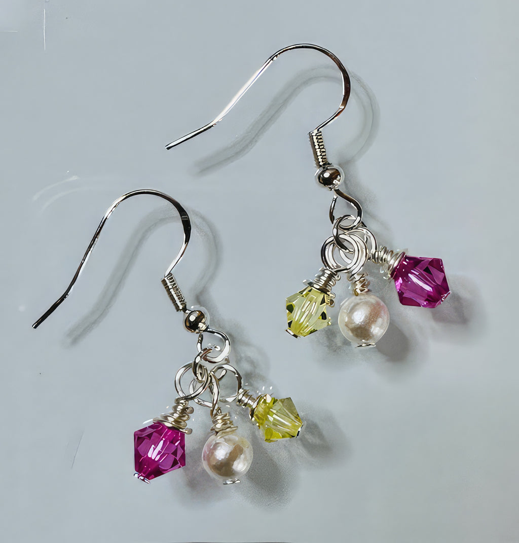 A pair of earrings featuring Swarovski crystals in pink and yellow, along with faux pearls, all connected by silver-coated copper wire on sterling silver ear wires.