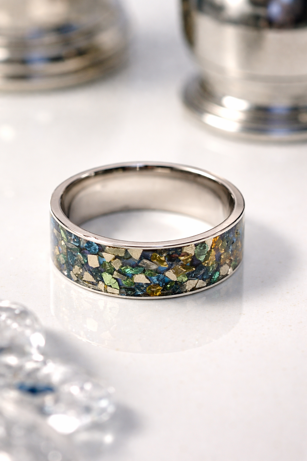 Stainless steel crushed glass ring displaying a colorful mosaic of amber, blue, green, and clear glass fragments.