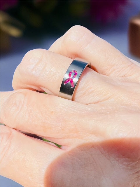 Pink awareness ribbon titanium ring worn on a hand as a symbol of hope, courage, strength, and support.