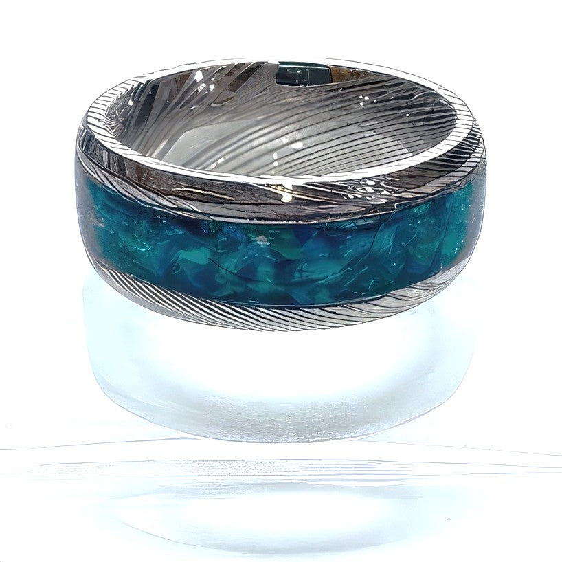 Top view of a handcrafted Damascus steel ring with a brilliant blue crushed opal inlay and flowing forged steel pattern.