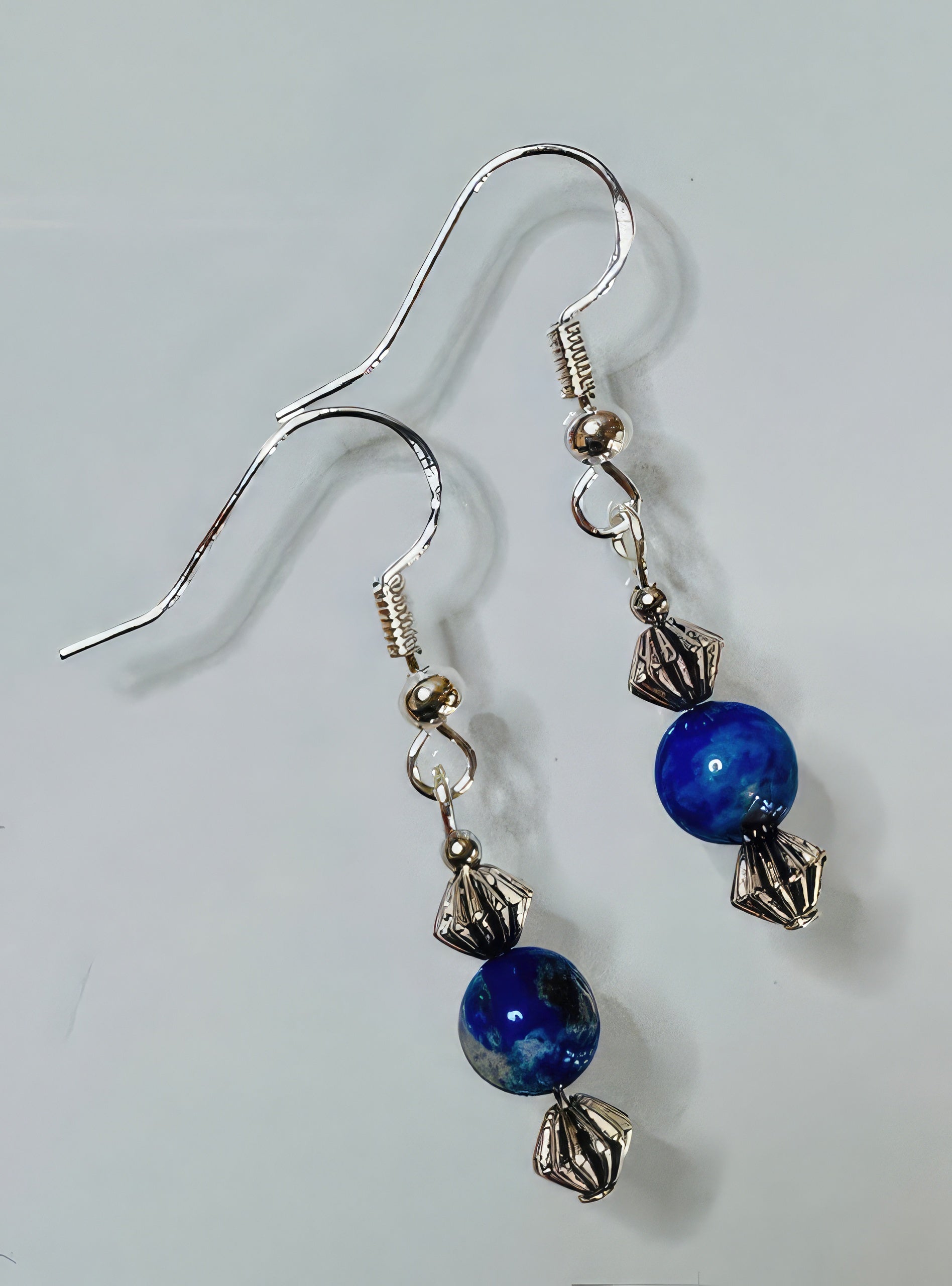 A pair of earrings featuring lapis lazuli stones with antiqued silver tone beads and sterling silver earwire.