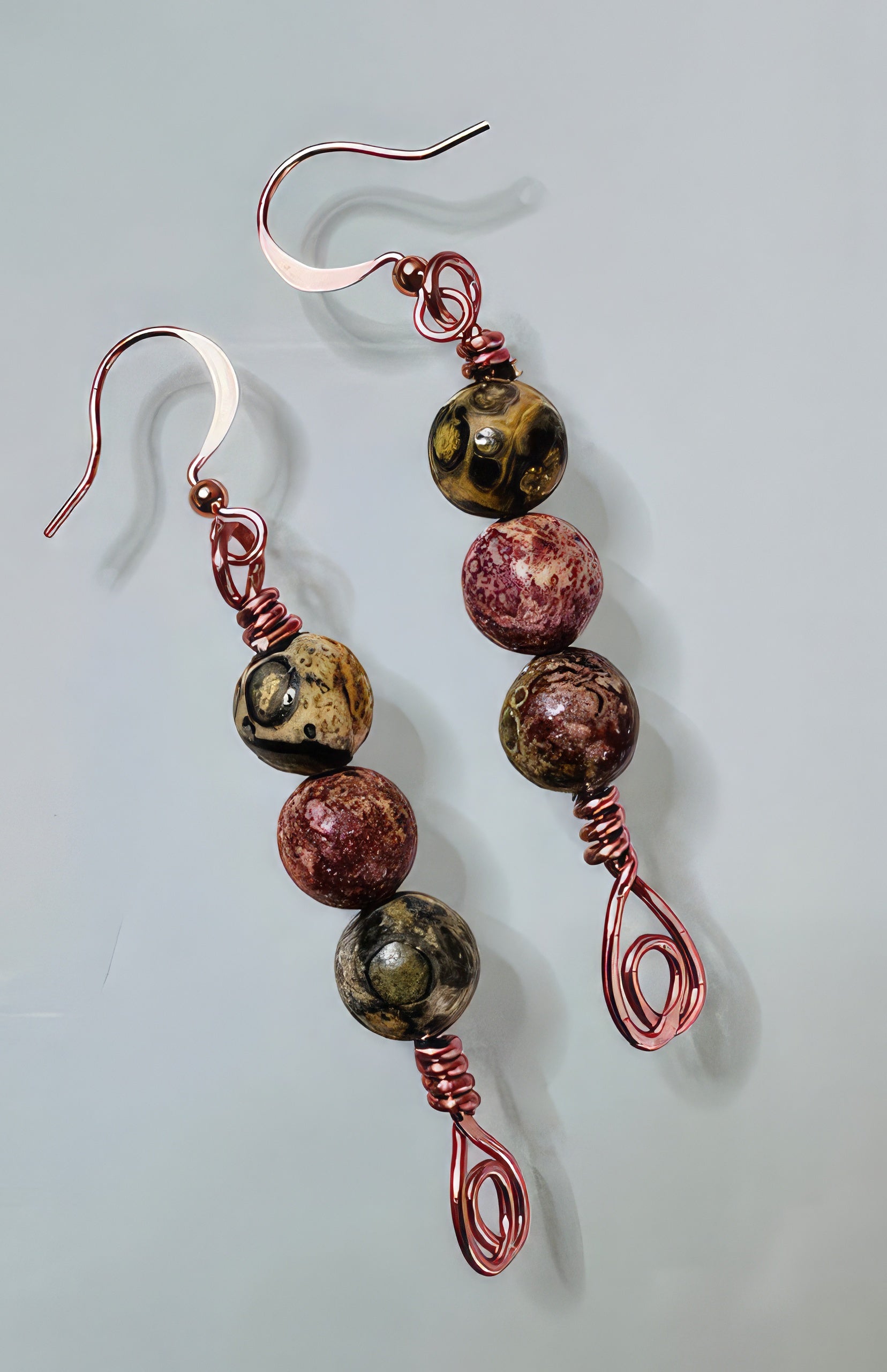 A pair of earrings featuring natural stones in earthy tones with copper-colored wire.