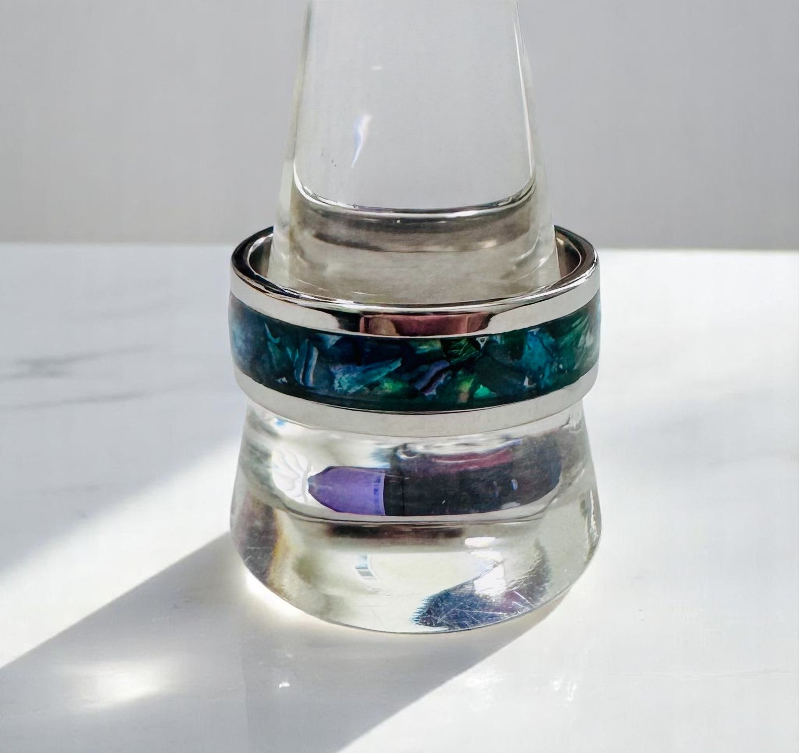 Incredibly vibrant and translucent paua shell chips intricately set into a gleaming silver band ring