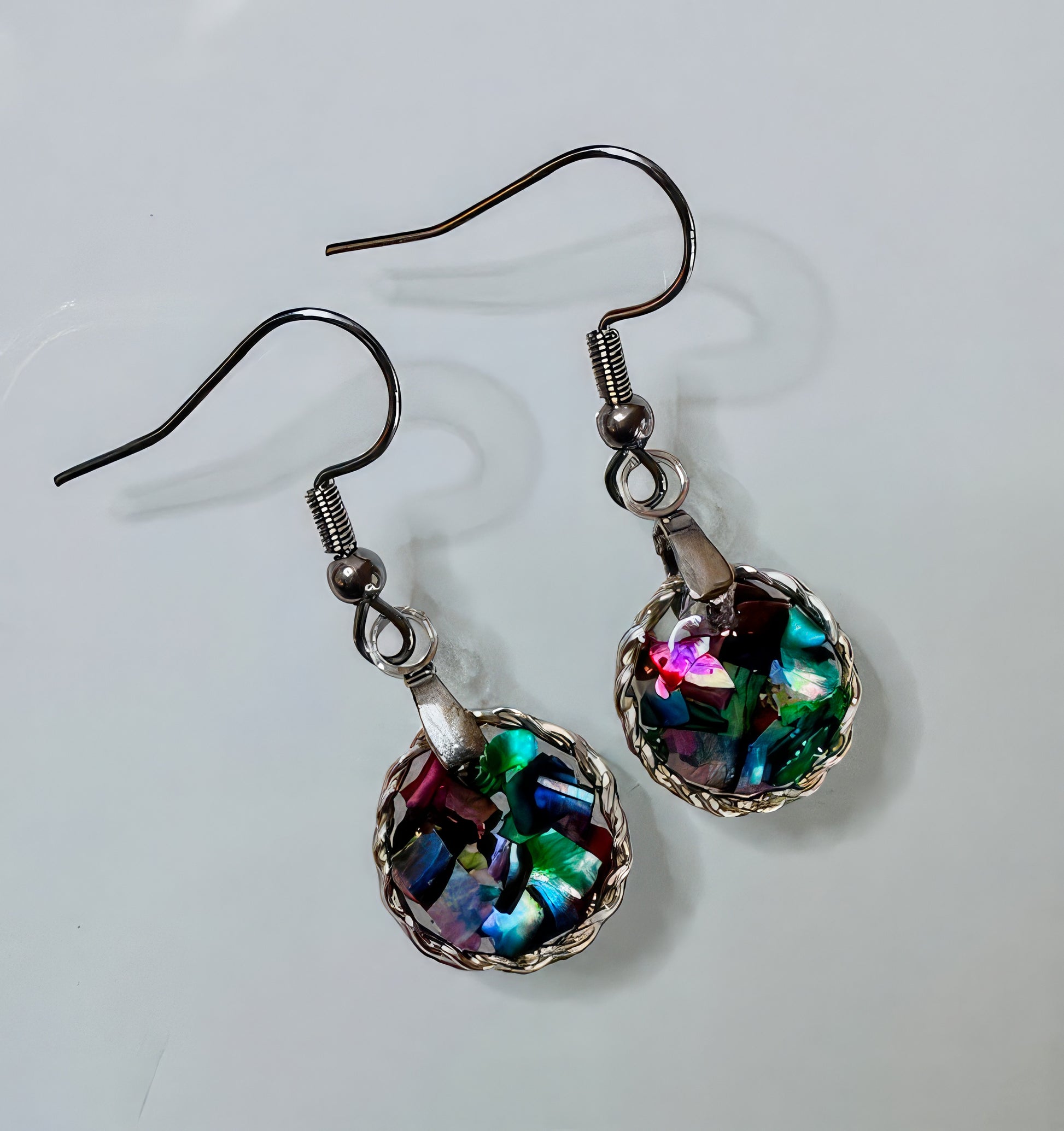A pair of earrings featuring a round, iridescent, resin bead with a silver wire frame and French earwire.