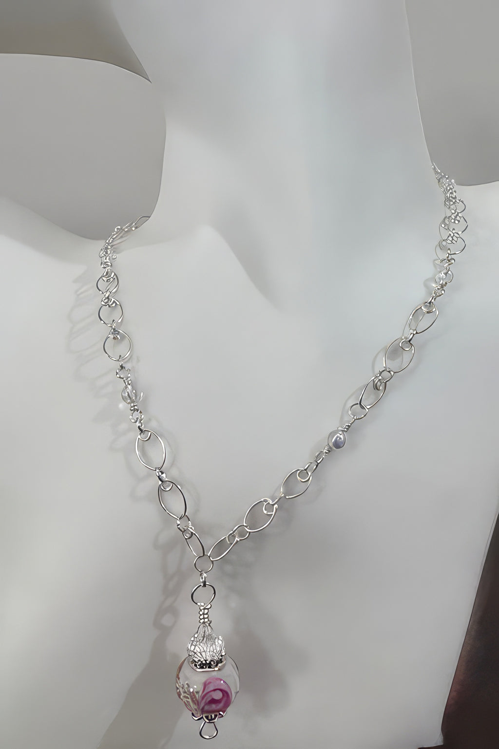 A silver-colored adjustable chain necklace with a glass lampwork bead pendant, displayed on a mannequin.