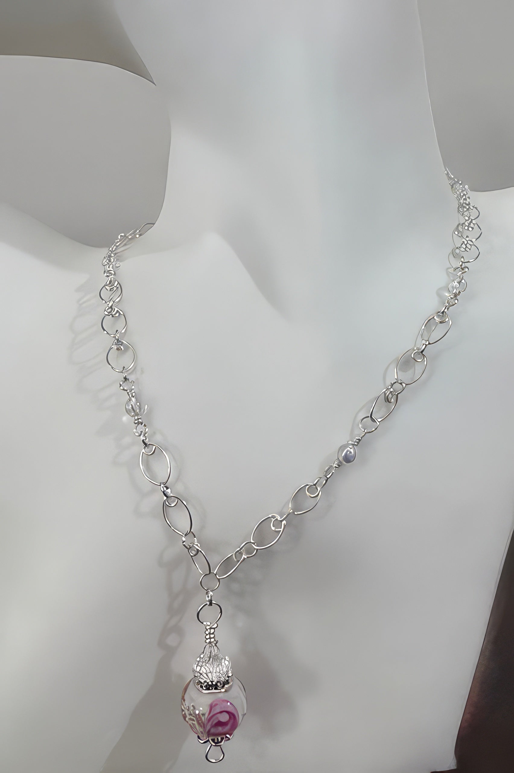 A silver-colored adjustable chain necklace with a glass lampwork bead pendant, displayed on a mannequin.