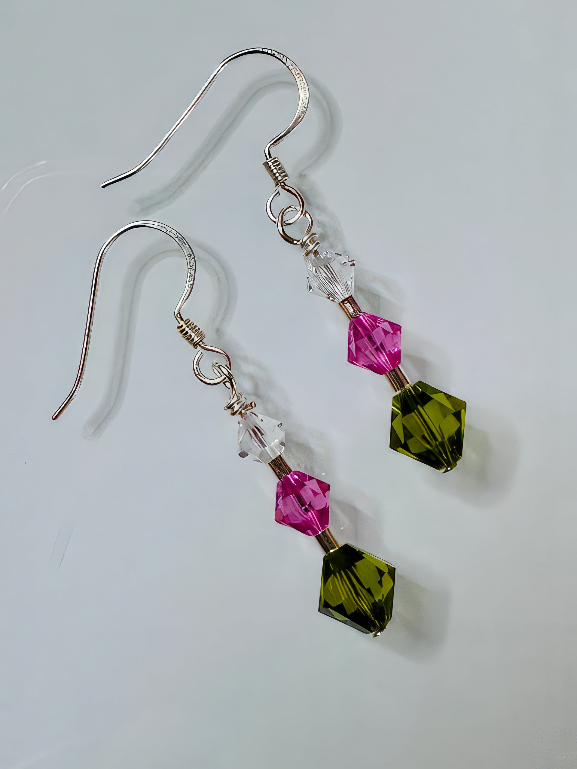 A pair of earrings featuring silver minis and Swarovski crystals in hot pink and forest green, attached to sterling silver earwire.