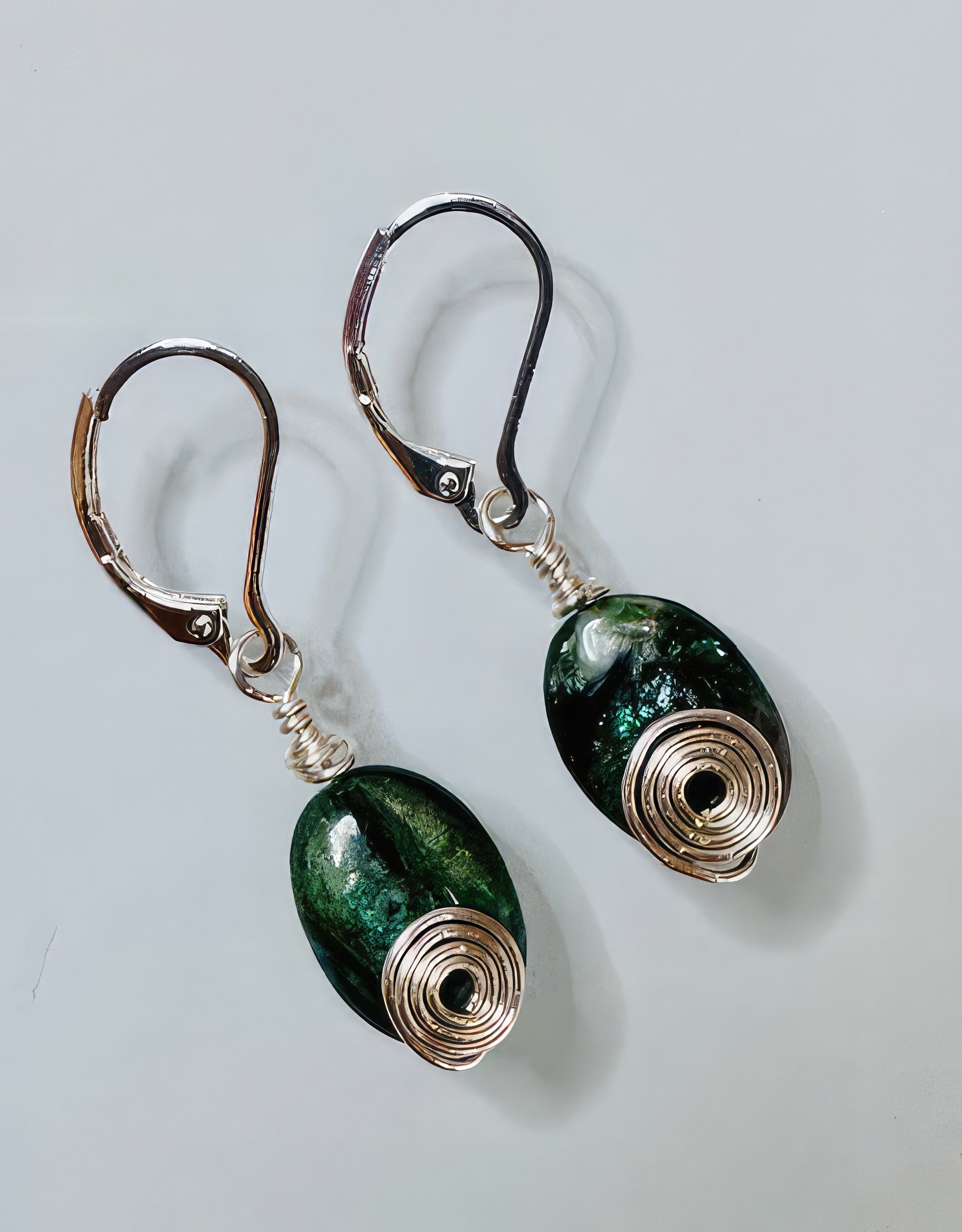 A pair of earrings featuring dark green ruby zoisite stones with spiral silver-filled wire wrap on hypoallergenic nickel-free ear wires.