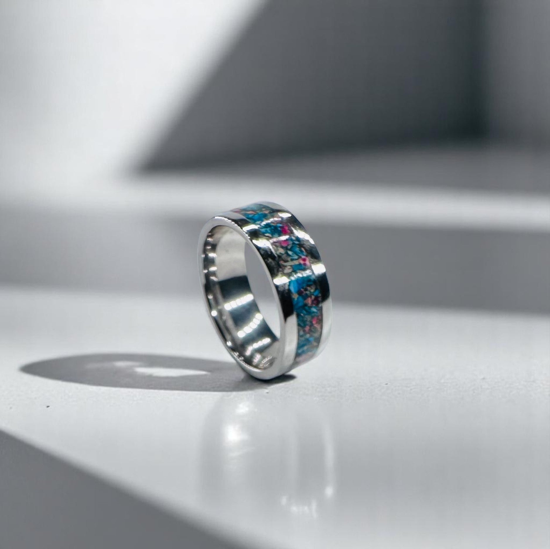 Colorful teal and rust-red stone chips set into a sleek silver band ring