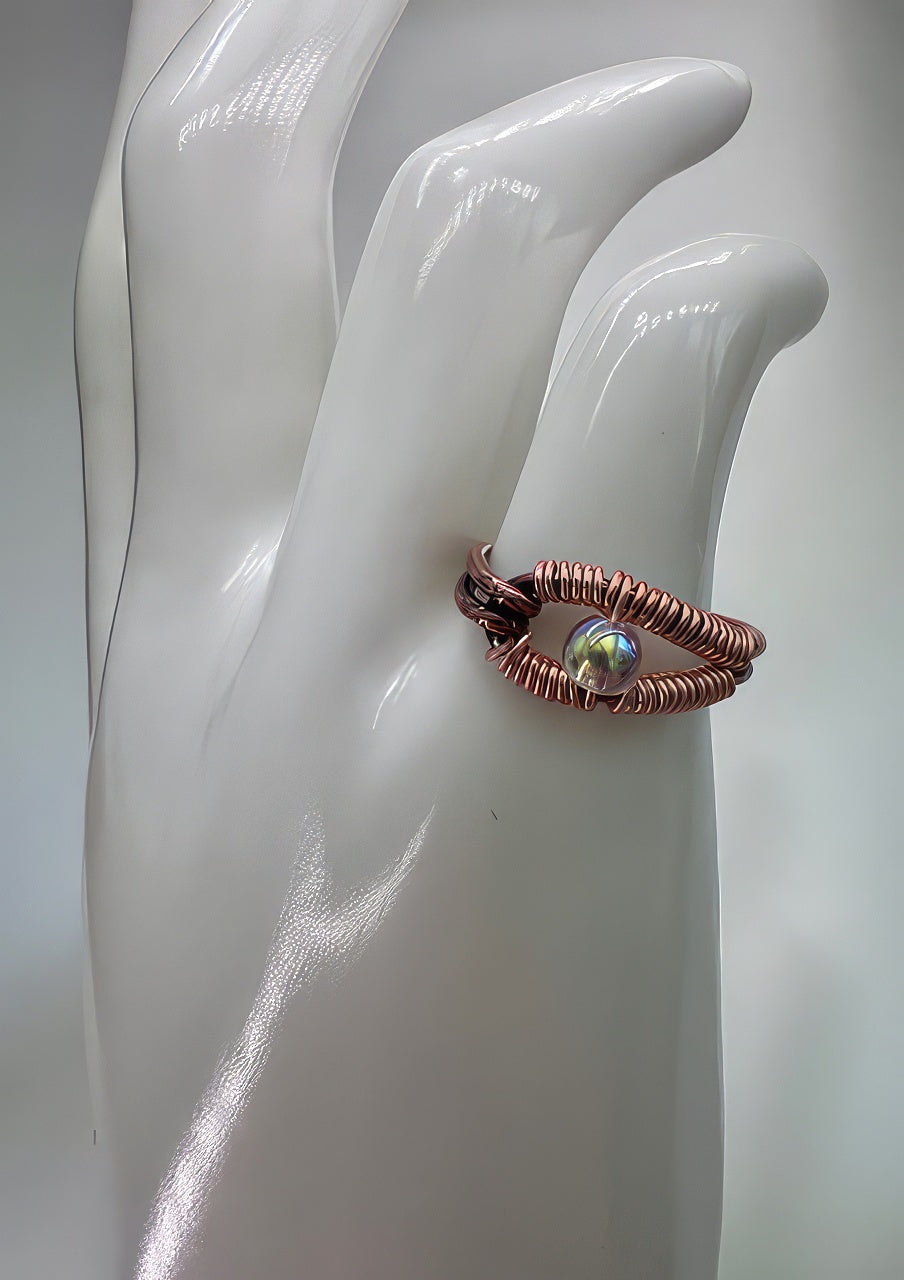 Treated shiny copper ring with hand-woven iridescent bead focal element
