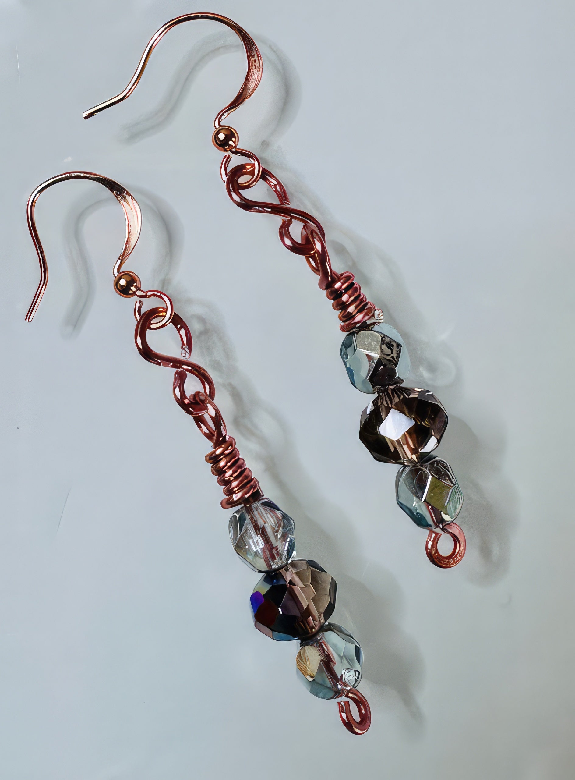 A pair of earrings featuring faceted Czech glass beads in clear and plum colors, with handmade copper links and non-tarnish coating.