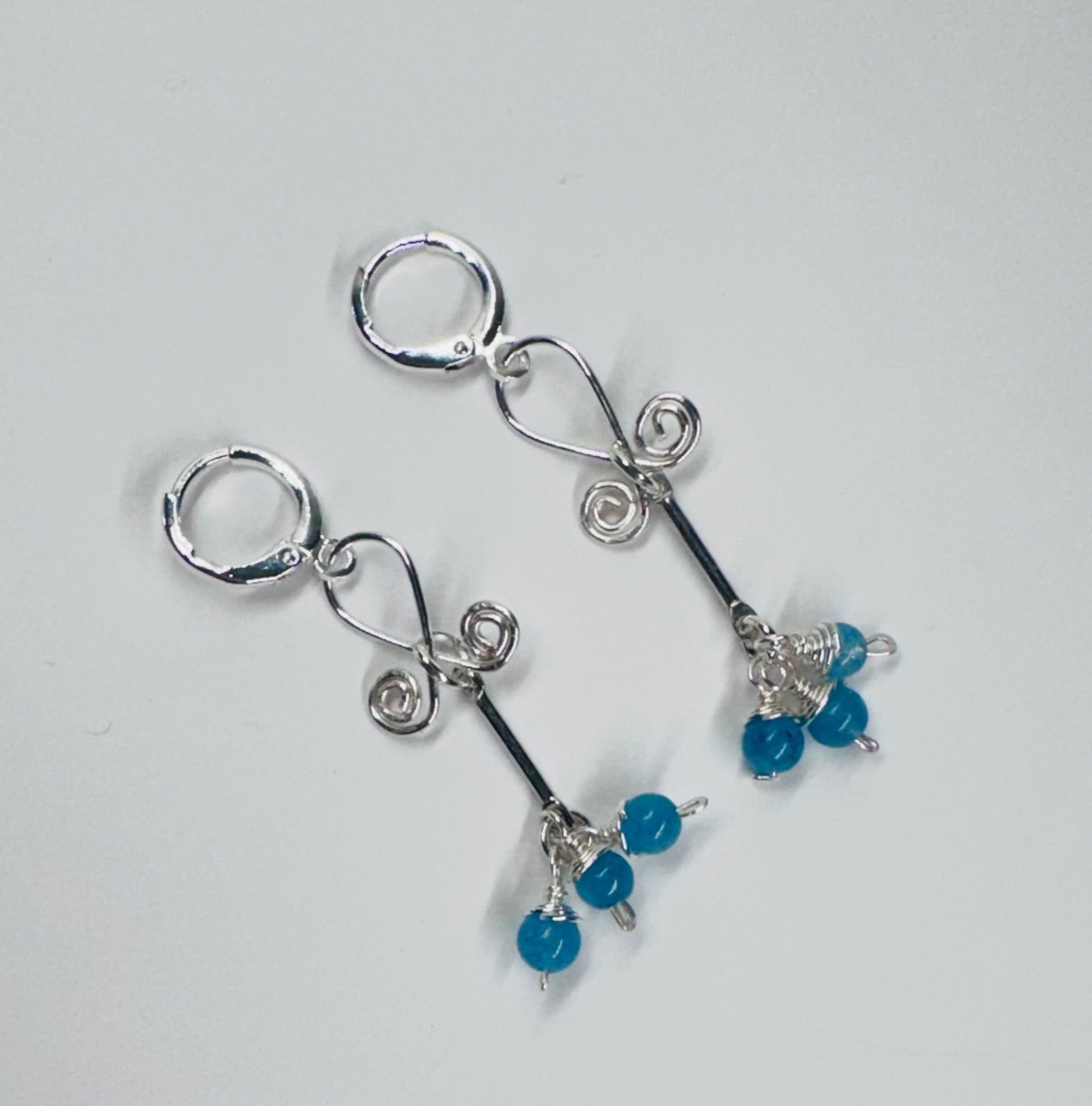 A pair of earrings featuring silver-colored wire curls and blue chalcedony stones with a secure round leverback closure.